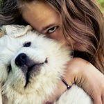 Happy teen girl embracing a cute puppy of a pyrenean mountain do